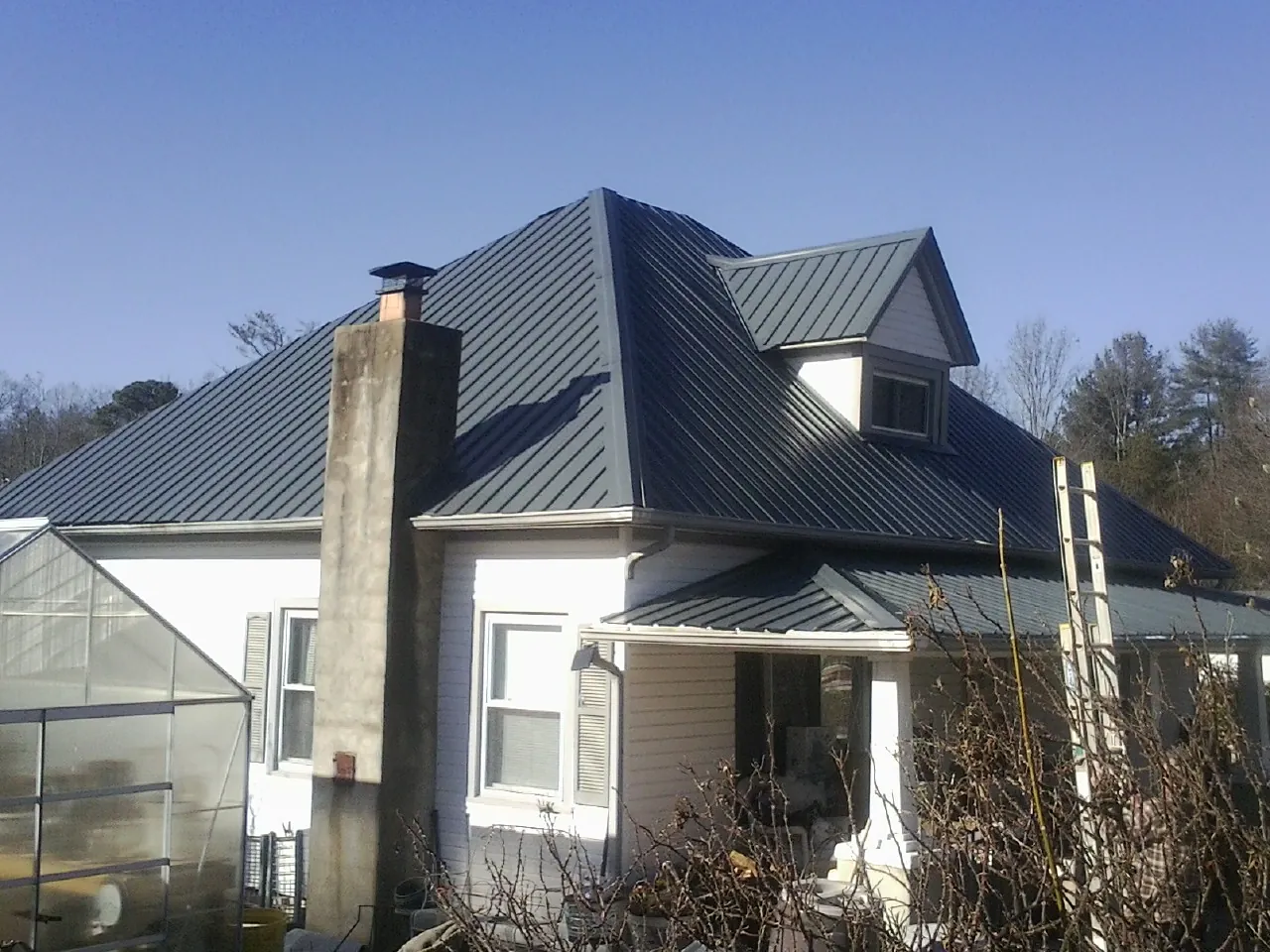 Dark blue standing seam metal roof on a white farmhouse with dormer — Slate & Tile Roof Repair by Roofing Brothers in Glen Rock