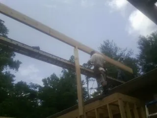 Carpenter setting a ridge beam over a new addition frame — Ice Dam Removal by Roofing Brothers in Glen Rock