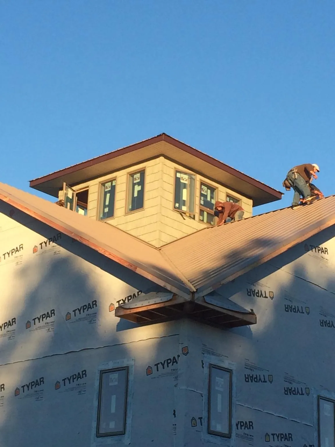 Roofers working around a rooftop cupola on a new metal roof at sunset — Roof Waterproofing in Glen Rock by Roofing Brothers